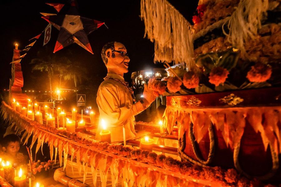 Locals meticulously light candles on a traditional fire boat as preparations begin for Boun Lai Heau Fai
