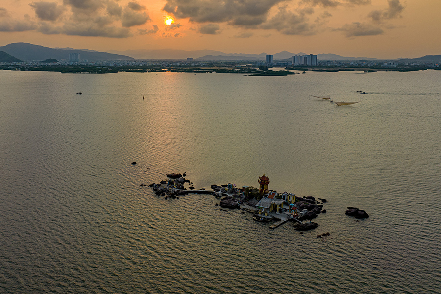 Sunset over Thi Nai Lagoon with a small shrine on rocky islet.