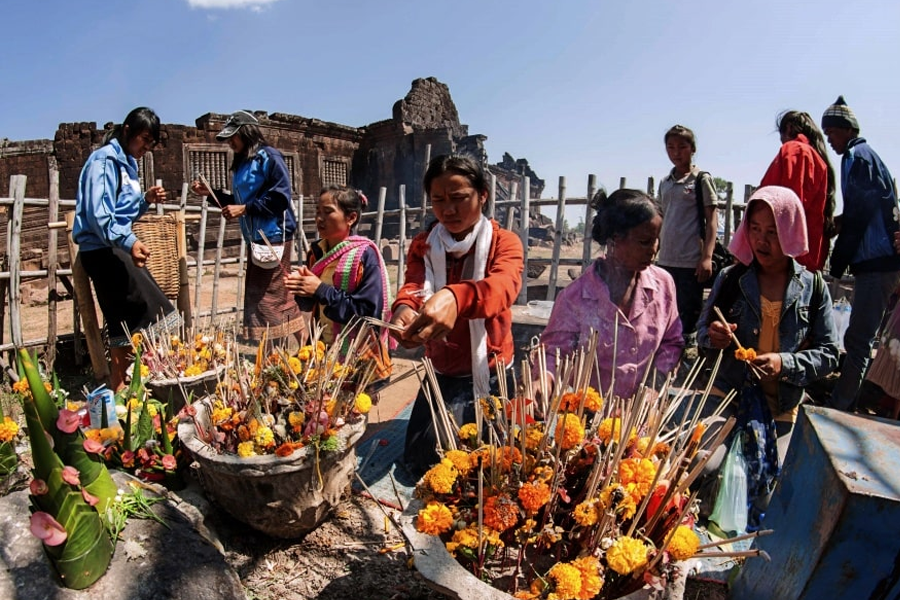 People praying by burning incense sticks during Boun Wat Phou