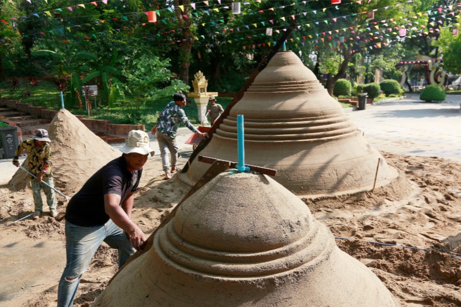 Men shaping traditional sand mounds in temple courtyard
