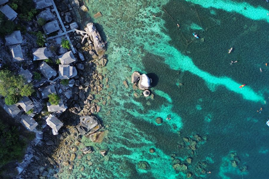 Discover the stunning coastline and clear blue waters of Ko Tao, Thailand, from above.