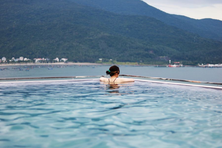 A woman is enjoying a peaceful moment in an infinity pool with a beautiful view of Da Nang