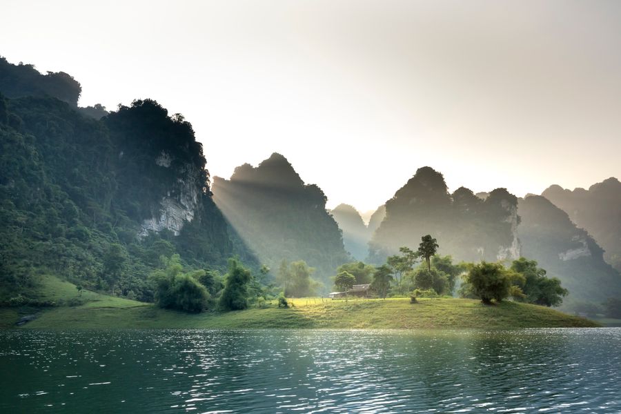 A peaceful landscape featuring sun-drenched mountains and a tranquil lake in Tuyen Quang, Vietnam.