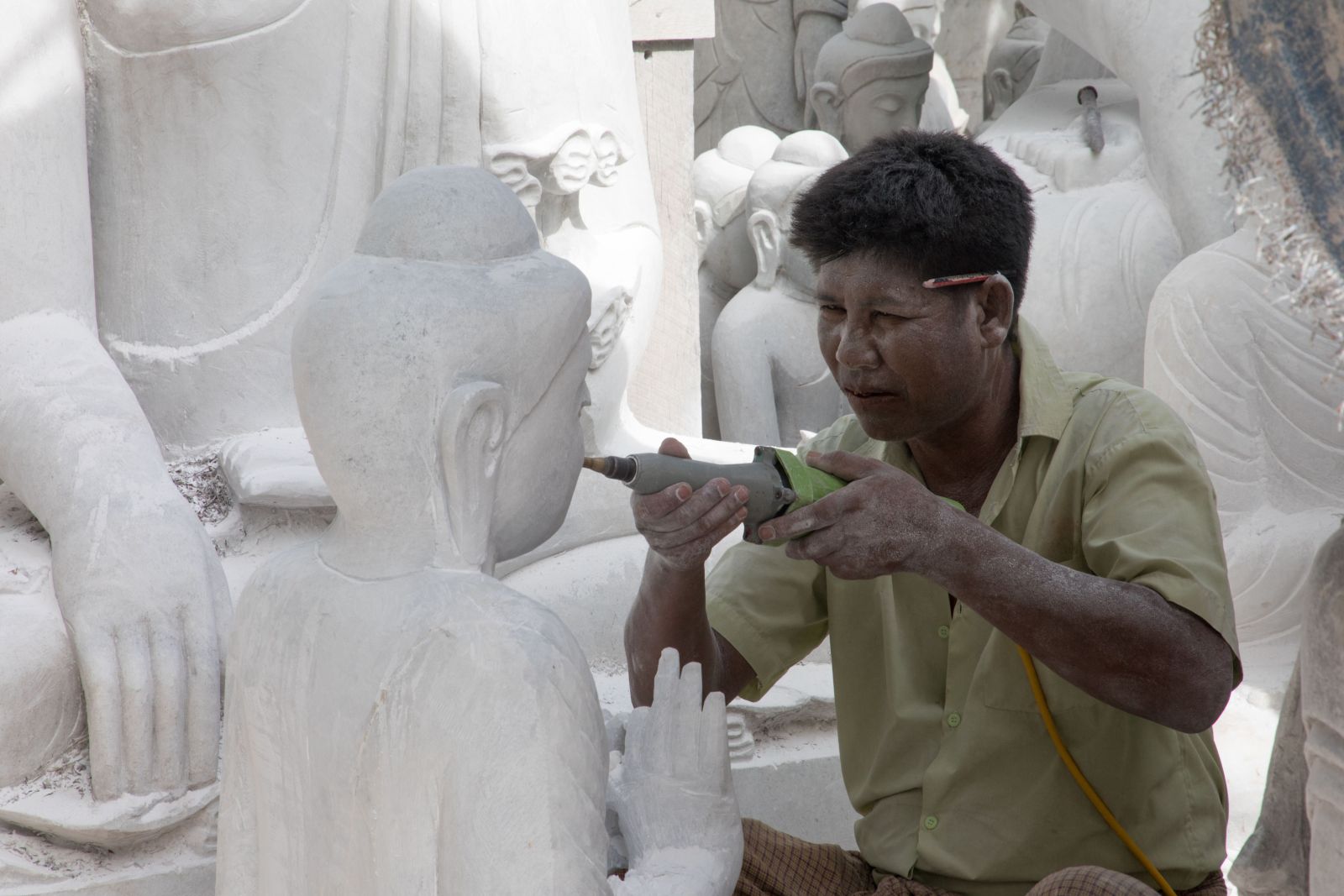A talented sculptor is working on a marble Buddha statue, focusing on intricate details