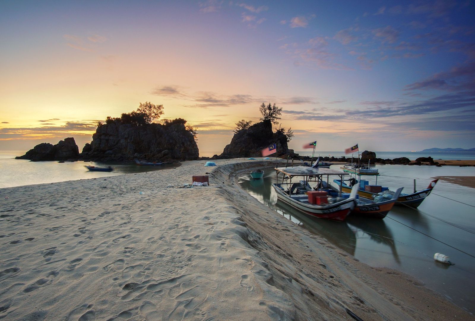 A peaceful scene of fishing boats at dawn on a sandy beach with calm waters.