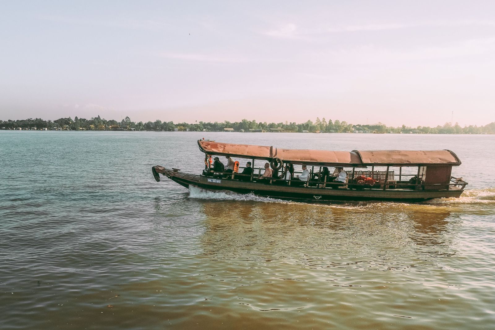 A beautiful view of a traditional boat traveling on the Mekong River in Vinh Long, Vietnam.