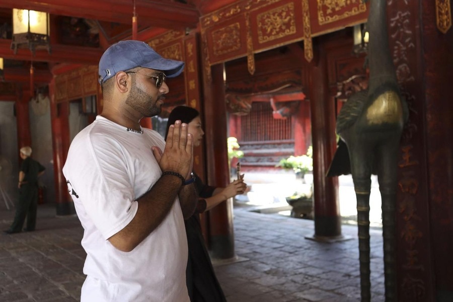 A visitor is offering incense and praying at the Temple of Literature. Photo: VnExpress