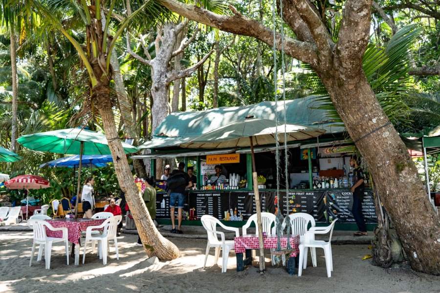 Dining at Banana Beach with ocean waves and swaying palm trees