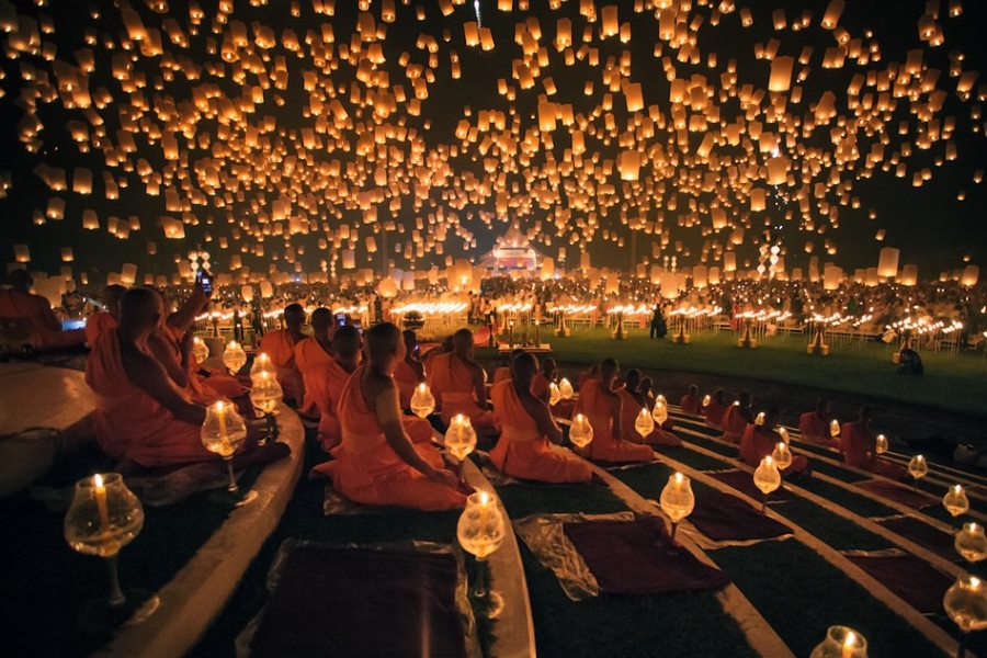 Monks gathered under a tree adorned with colorful lanterns during Yi Peng Festival in Chiang Mai